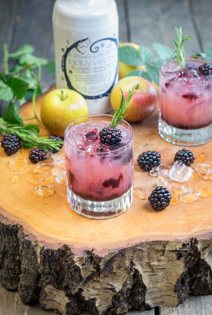 Bottle of Holy Grass Vodka and Holy Grass apple and blackberry cocktail served in two old fashioned glass and garnished with blackberries and thyme sprig