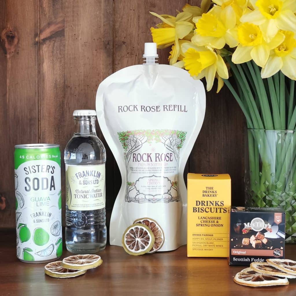 Content of the Refill Rewards Club box for March 2021 including Rock Rose Gin pouch, guava lime soda, tonic water, cheese and onion biscuits and Scottish Fudge